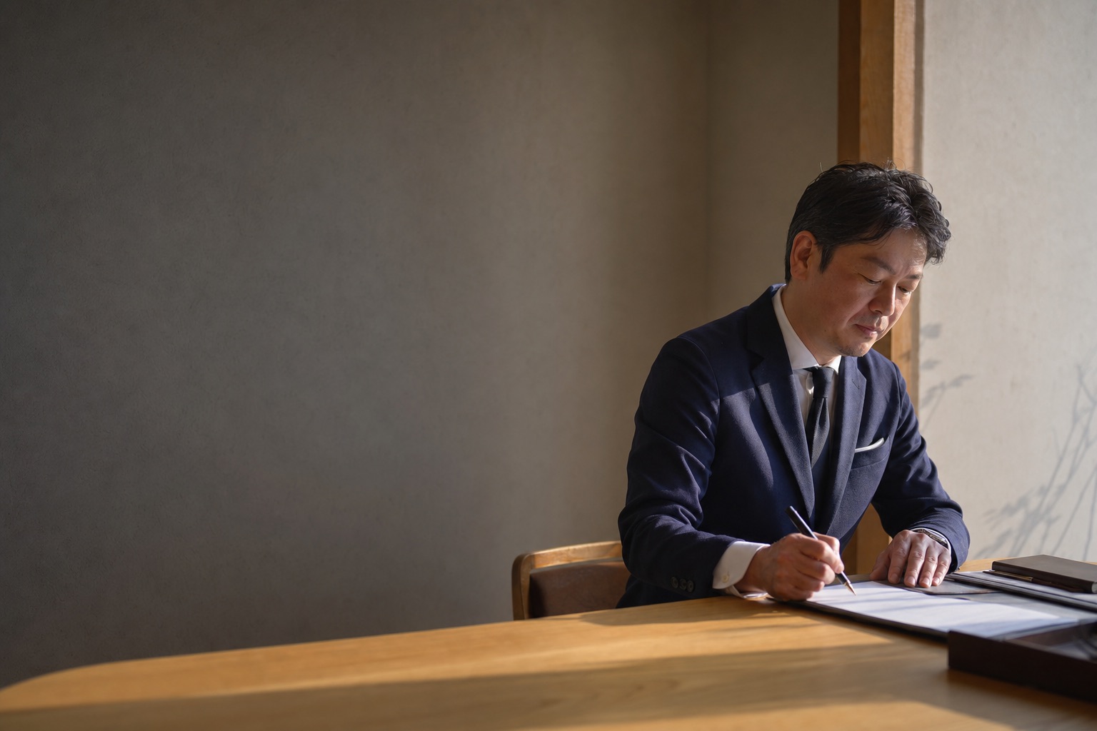 事務所の机で書類に向かう士業の先生